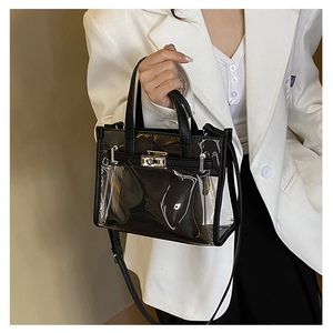 Detail of transparent Kelly style bag with black trim and silver turn-lock closure
