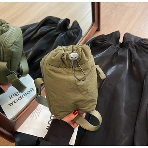 Detail of army green nylon crossbody bag with drawstring closure and black strap