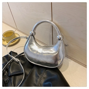 Detail of silver crescent handbag with metallic spheres and adjustable strap on black leather