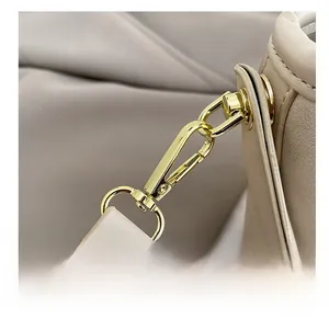Close-up of premium gold-tone metal hook and strap connector on beige leather bucket bag