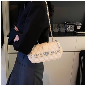 Detail of beige quilted flap bag with rhinestone square buckle and chain strap