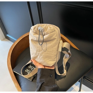 Close-up of beige nylon drawstring crossbody bag with zipper and adjustable strap