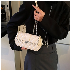 Close-up of white quilted crossbody bag with classic chain strap on model shoulder