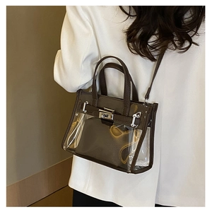 Detailed view of clear PVC Kelly bag with premium brown leather trim and metal clasp lock