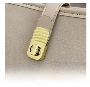Close-up of golden metal twist lock and stitching on beige suede leather bucket bag
