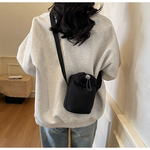 Minimalist black drawstring nylon bag with silver bead chain detail shown on a shoulder