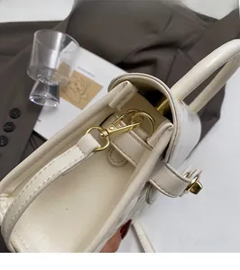 Macro di una piccola borsa in pelle crema con chiusura dorata e dettagli interni