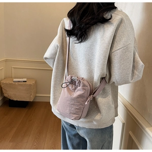 Detail view of pink nylon drawstring crossbody bag with textured fabric and adjustable strap