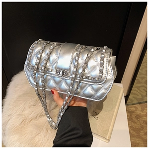 Close-up of a silver quilted chain bag with a metallic finish and a rotary lock clasp