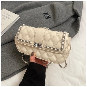 Detailed macro view of cream quilted leather texture and metallic clasp on chain bag