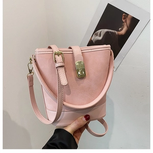 Detail of pink bucket bag featuring gold twist-lock and mixed matte leather textures