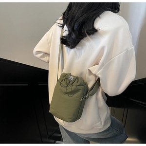 Detail of adjustable strap and drawstring closure on olive green nylon crossbody bag