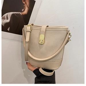 Detail of cream bucket bag featuring gold twist lock and stylish adjustable strap