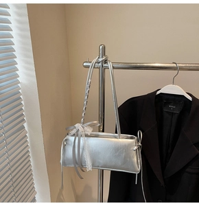 Detail of silver rectangular crossbody bag with lace bow decoration and metallic finish