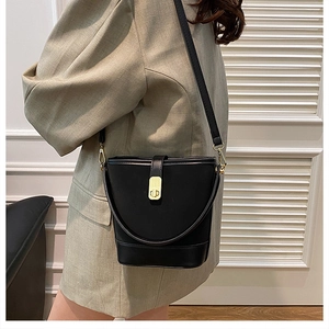 Detail view of the elegant black bucket bag featuring a polished gold twist-lock closure