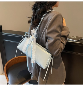 Detail of light blue glossy shoulder bag featuring a white lace bow in balletcore style