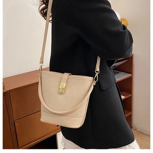 Chic beige leather bucket bag styled with a black blazer featuring a gold twist lock