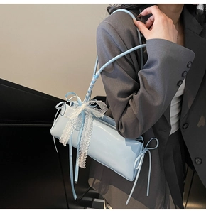 Detail of light blue pleated pillow bag with delicate white lace bow and silk ribbons