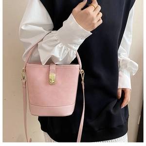 Detail of pink PU leather bucket bag with gold metal lock and adjustable shoulder strap