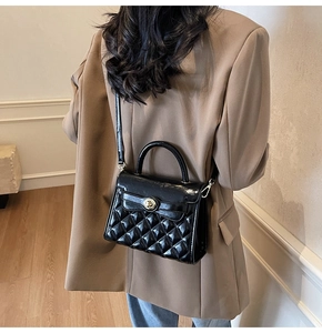 Dettaglio borsa trapuntata nera con chiusura a rotazione oro su blazer color beige