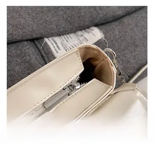 Gros plan d'un sac en cuir beige avec fermeture éclair argentée et détails métalliques