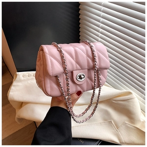 Detail of pink quilted crossbody bag with silver chain strap and metal turn-lock