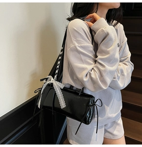 Detail of black patent leather bag featuring white lace bow and Balletcore aesthetic