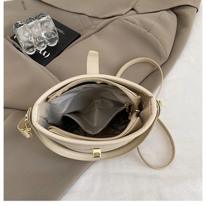 Detailed interior of a beige bucket bag showing multi-layer compartments and chevron lining