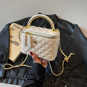 Chic quilted beige bucket bag with gold handle and chain strap on leather background