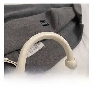 Détail du sac à main crème élégant avec breloques boules et poignée arrondie