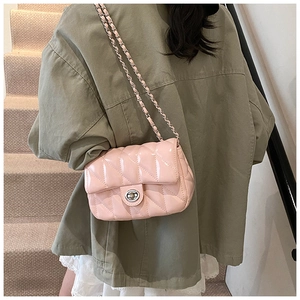 Detail of pink quilted patent leather bag with silver chain strap on model