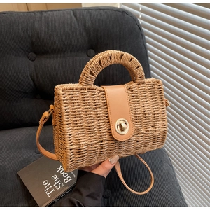 Detail of woven straw handbag featuring a camel leather flap and golden twist lock