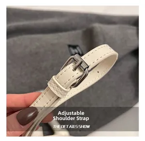 Détail de la bandoulière réglable en cuir crème avec boucle argentée et surpiqûres