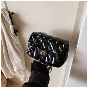Detail of black quilted leather crossbody bag with silver metal chain strap and twist lock