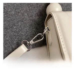 Détail des finitions métalliques argentées et de la sangle en cuir du sac blanc
