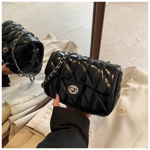 Detail of black quilted leather shoulder bag with silver chain strap and metal clasp