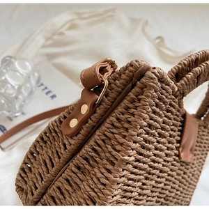 Close-up of woven straw bag texture with leather handle and golden hardware detail