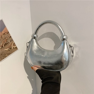Silver metallic crescent handbag with circular handle and mirror finish texture