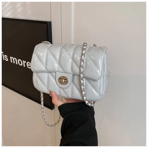Close-up of quilted light blue shoulder bag with silver chain strap and metal turn-lock