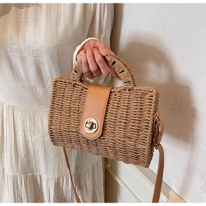 Detail of hand-woven straw bag with tan leather flap and golden twist lock closure