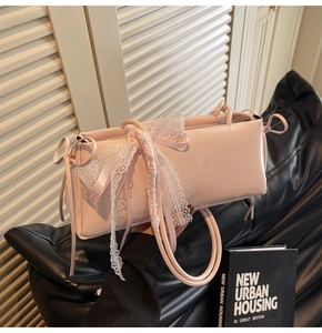 Close-up of pink glossy pleated pillow bag with delicate white lace bow detail