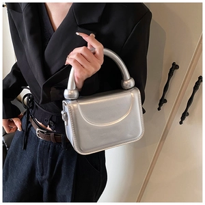 Détail d'un mini sac argenté avec poignée épaisse et finitions sphériques design