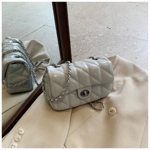 Detail of light blue quilted crossbody bag with silver chain strap and metal lock closure