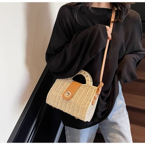 Close-up of handmade straw crossbody bag with leather trim and gold metal lock