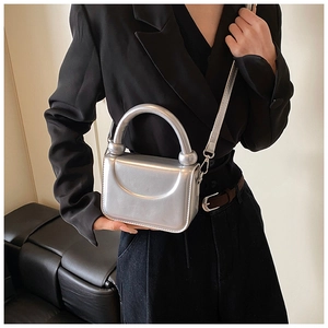Mini sac argenté effet miroir avec détail croissant porté sur un blazer noir