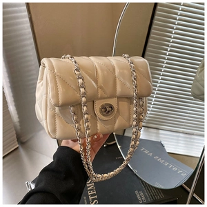 Detail of cream quilted crossbody bag featuring silver chain strap and metal rotary lock