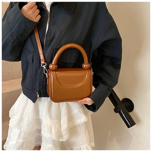 Détail du petit sac carré marron caramel avec poignée ronde et texture en cuir lisse