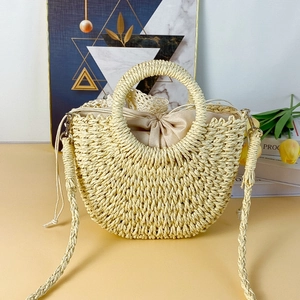Detail of hand-woven beige crescent bag with satin drawstring lining and round handles