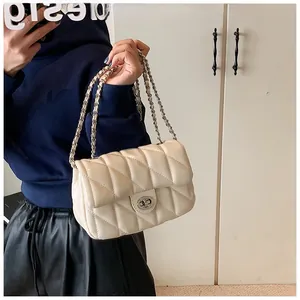Detail of cream quilted crossbody bag with metal twist lock and chain strap