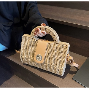 Detail of handmade straw bag featuring brown leather flap and silver metal turn-lock